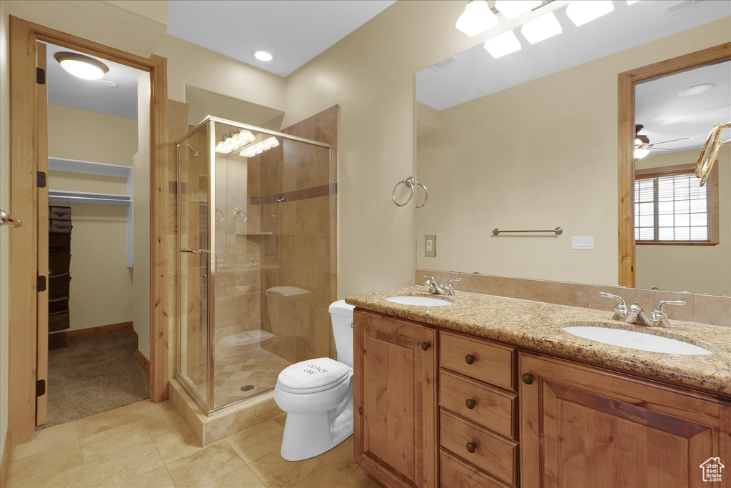 Bathroom with walk in shower, oversized vanity, toilet, tile floors, and ceiling fan