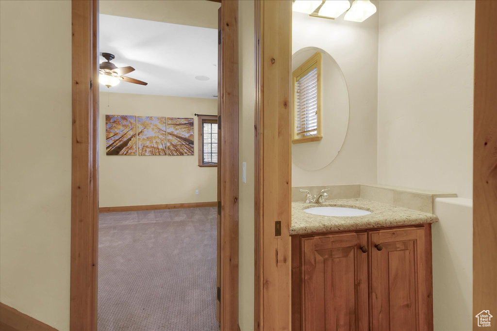 Bathroom with ceiling fan and vanity with extensive cabinet space