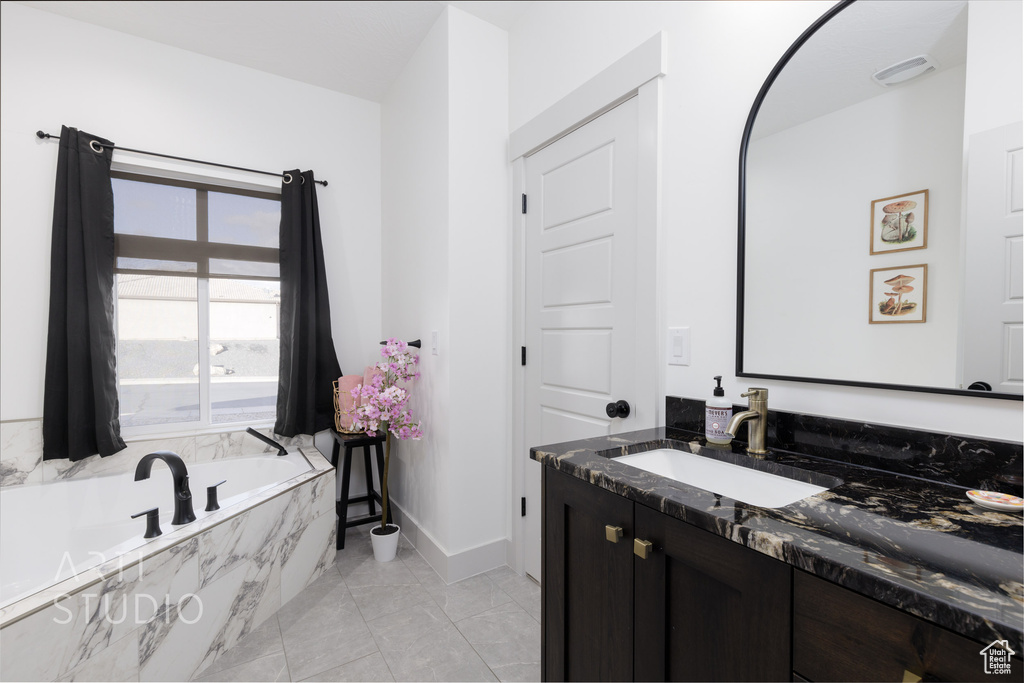 Bathroom featuring oversized vanity, tiled bath, and tile flooring