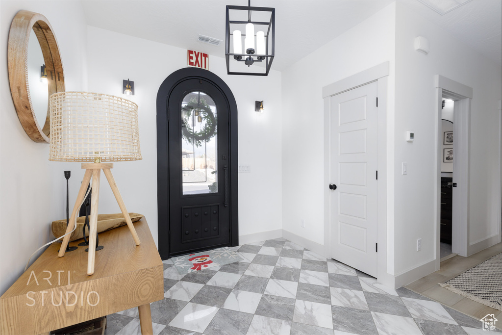Tiled entryway featuring a chandelier