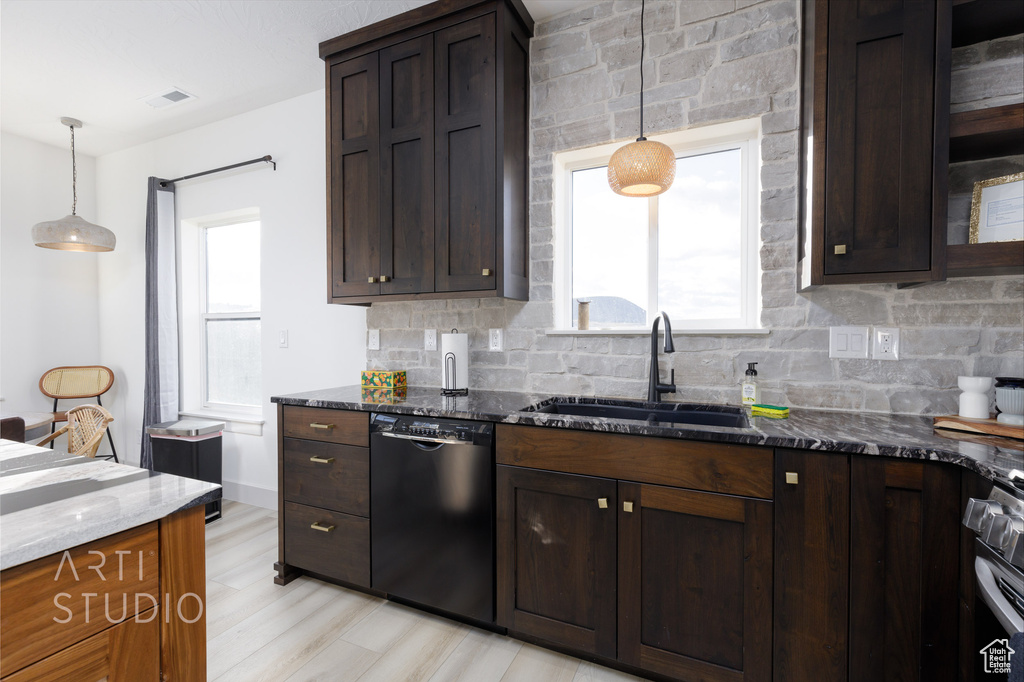 Kitchen with light hardwood / wood-style flooring, dishwasher, sink, dark stone countertops, and pendant lighting