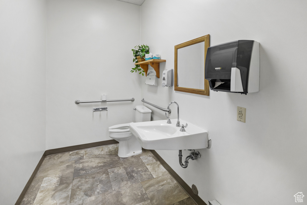 Bathroom featuring toilet, sink, and tile flooring