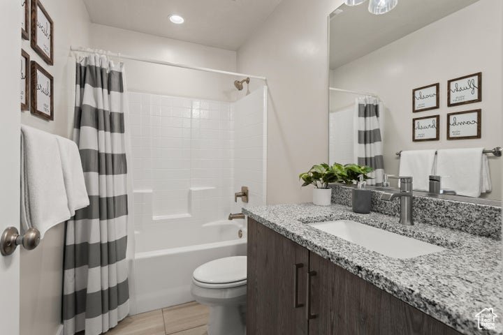 Full bathroom with shower / tub combo, tile floors, oversized vanity, and toilet