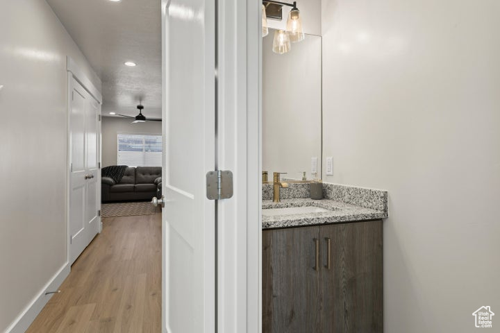 Bathroom with large vanity, hardwood / wood-style floors, and ceiling fan