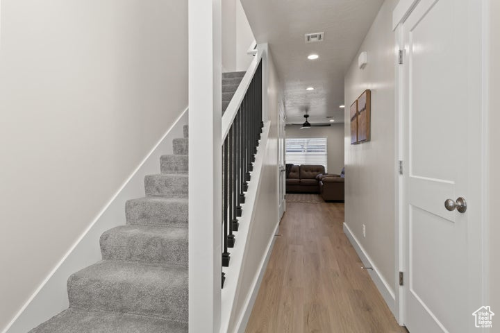 Stairway with light hardwood / wood-style flooring and ceiling fan