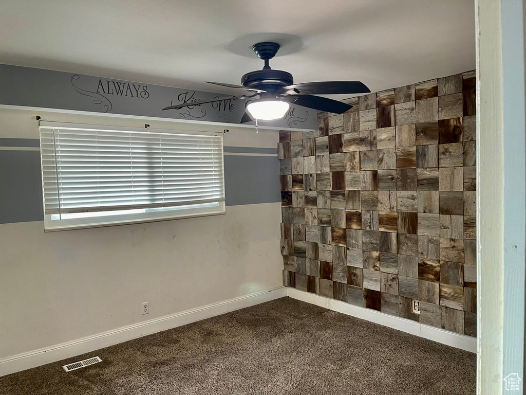 Spare room with dark colored carpet and ceiling fan