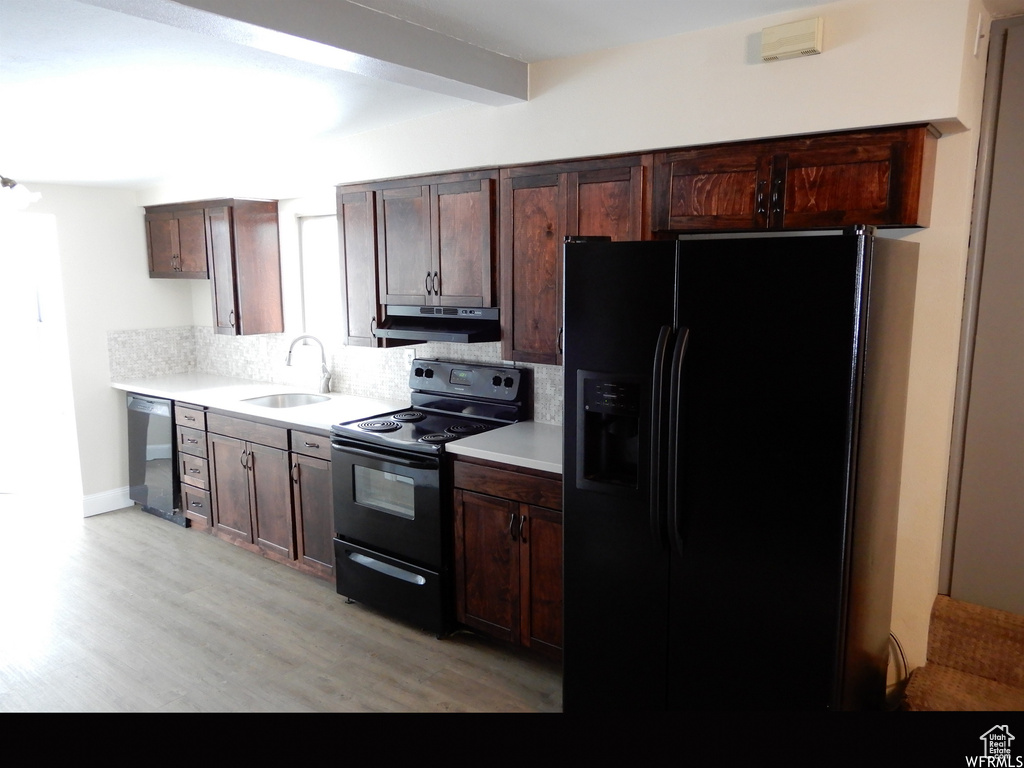 Kitchen featuring backsplash, dark brown cabinetry, light hardwood / wood-style floors, sink, and black appliances