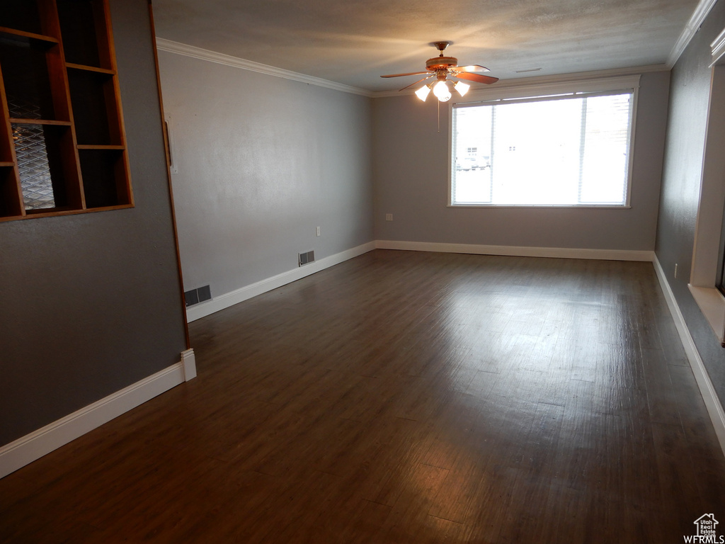 Unfurnished room featuring dark hardwood / wood-style flooring, ceiling fan, and ornamental molding