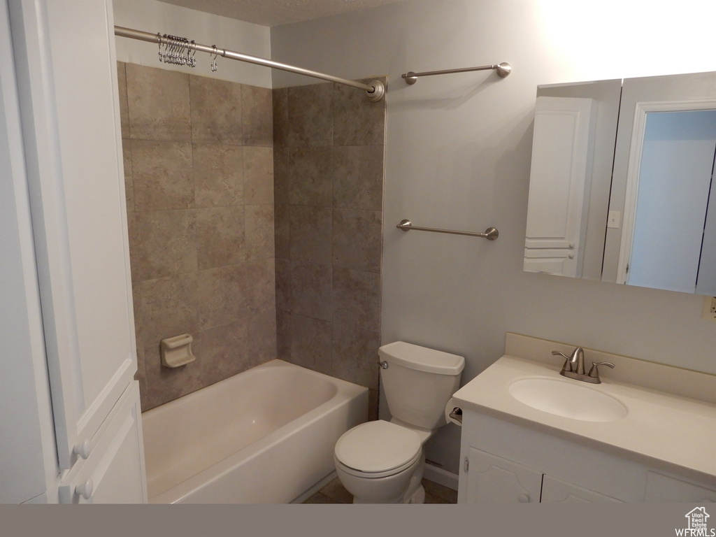 Full bathroom featuring vanity, tiled shower / bath combo, and toilet