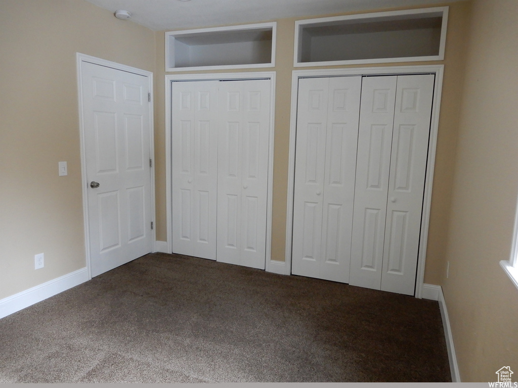 Unfurnished bedroom featuring two closets and dark colored carpet