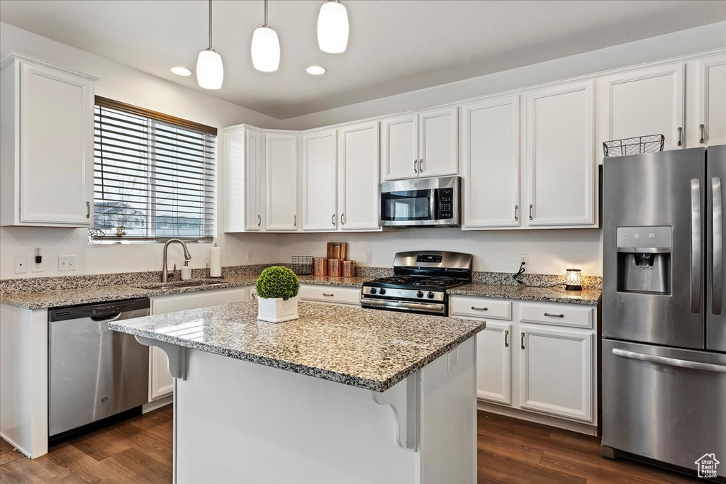 Kitchen featuring stainless steel appliances, white cabinetry, a breakfast bar area, dark hardwood / wood-style floors, and decorative light fixtures