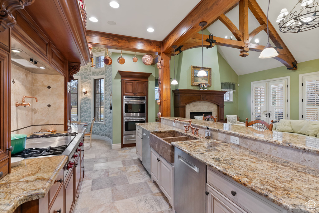 Kitchen with hanging light fixtures, stainless steel appliances, light stone counters, and light tile flooring