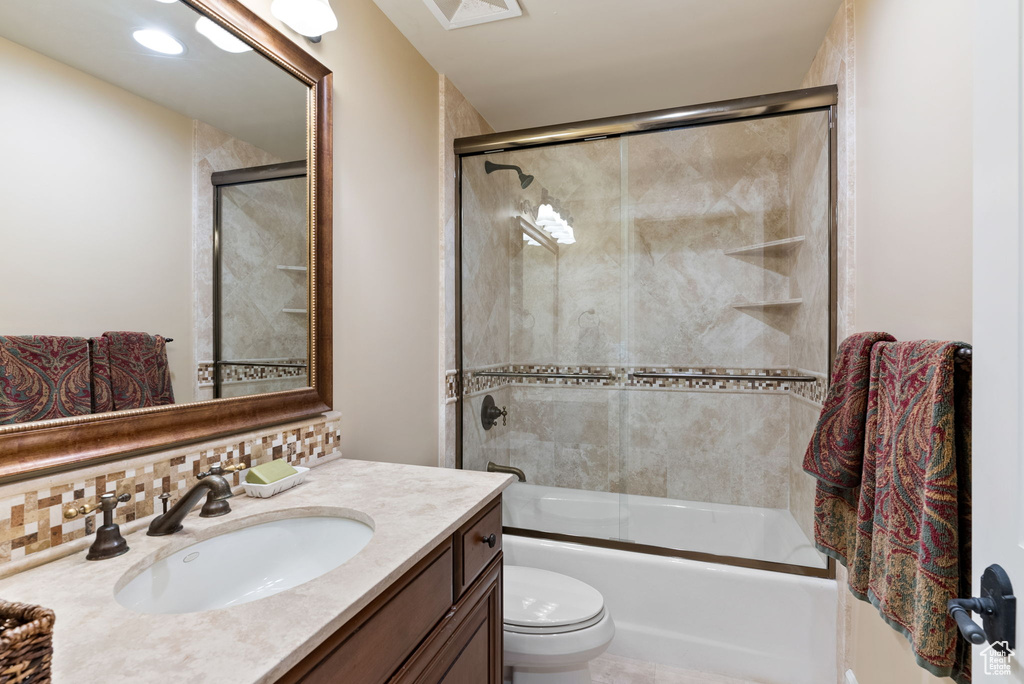 Full bathroom with vanity, toilet, enclosed tub / shower combo, and backsplash