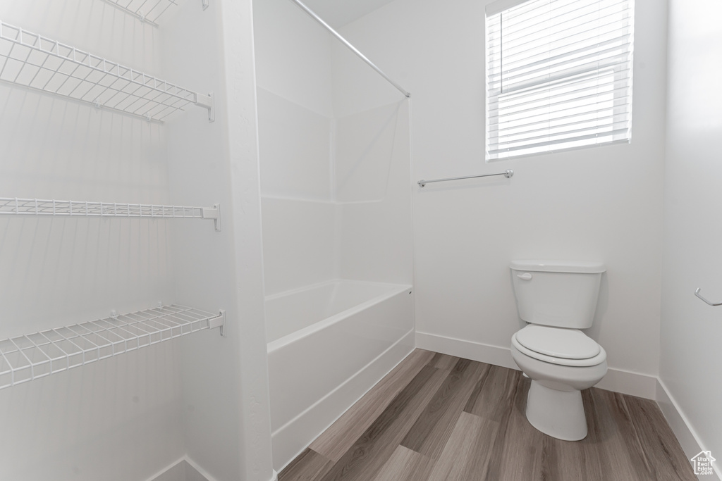 Bathroom featuring shower / tub combination, hardwood / wood-style flooring, and toilet