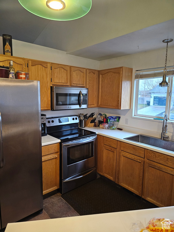 Kitchen featuring decorative light fixtures, stainless steel appliances, dark tile flooring, and sink