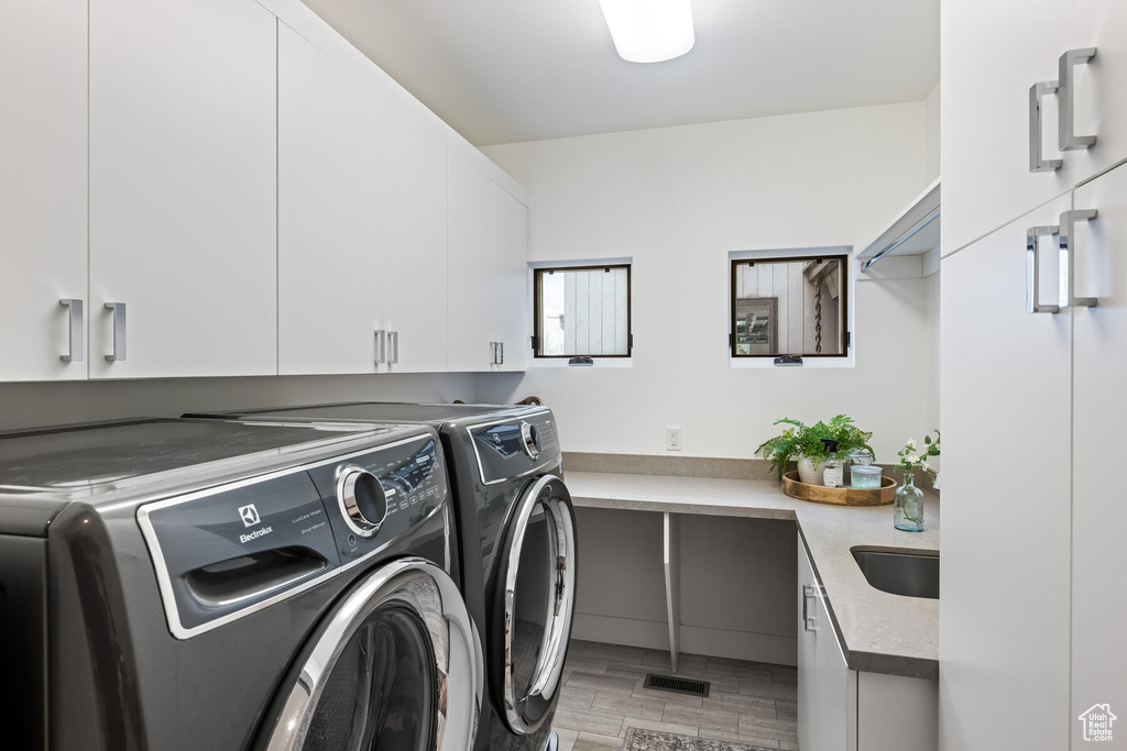 Laundry area with hardwood / wood-style flooring, washer and dryer, and cabinets