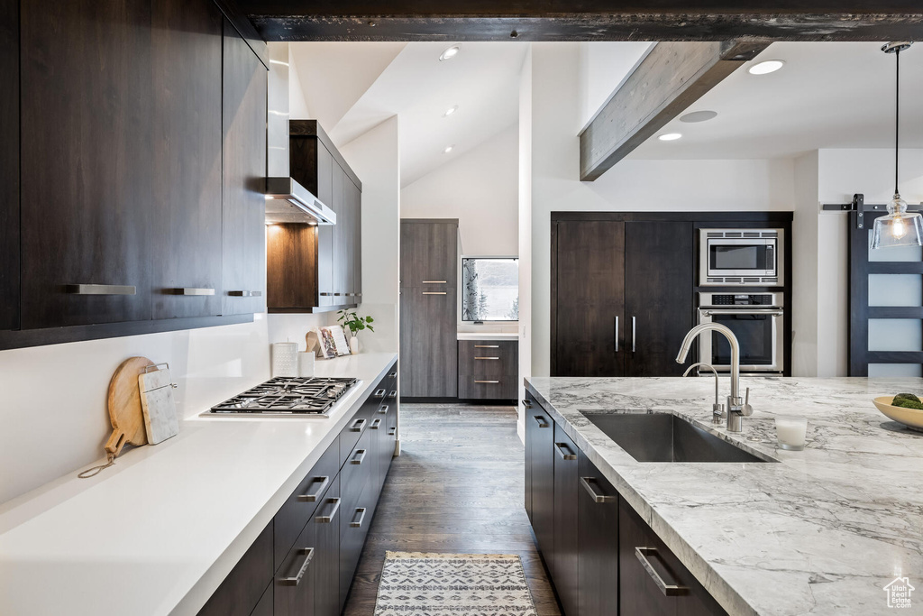 Kitchen featuring hanging light fixtures, appliances with stainless steel finishes, sink, dark hardwood / wood-style floors, and vaulted ceiling with beams