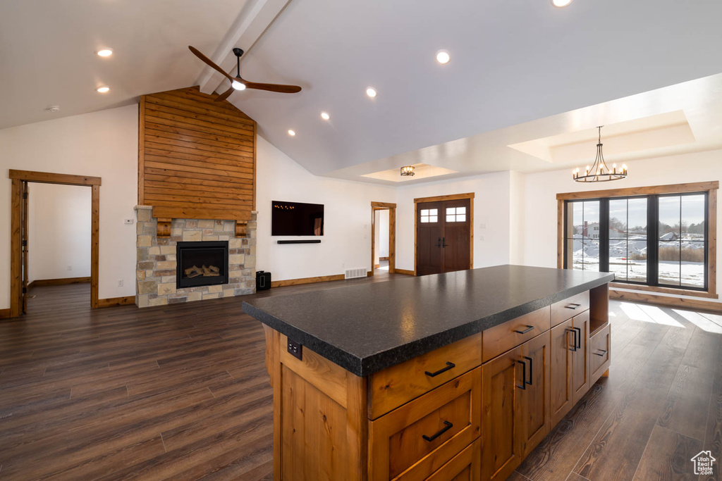Kitchen featuring ceiling fan with notable chandelier, wooden walls, dark wood-type flooring, and a center island