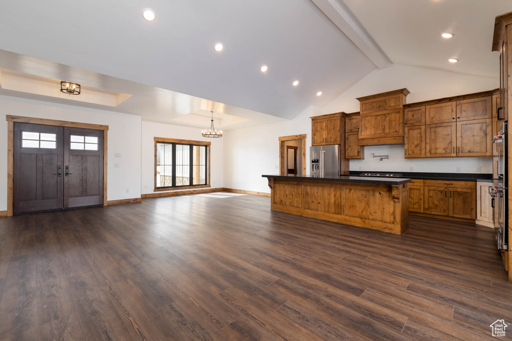 Kitchen featuring high quality fridge, a breakfast bar, a notable chandelier, and dark hardwood / wood-style flooring