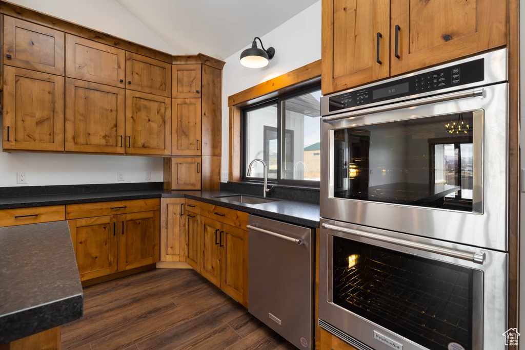 Kitchen with dark hardwood / wood-style flooring, sink, appliances with stainless steel finishes, and lofted ceiling