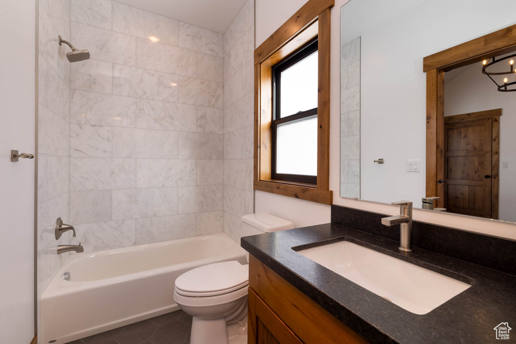 Full bathroom with vanity, toilet, tile floors, and tiled shower / bath