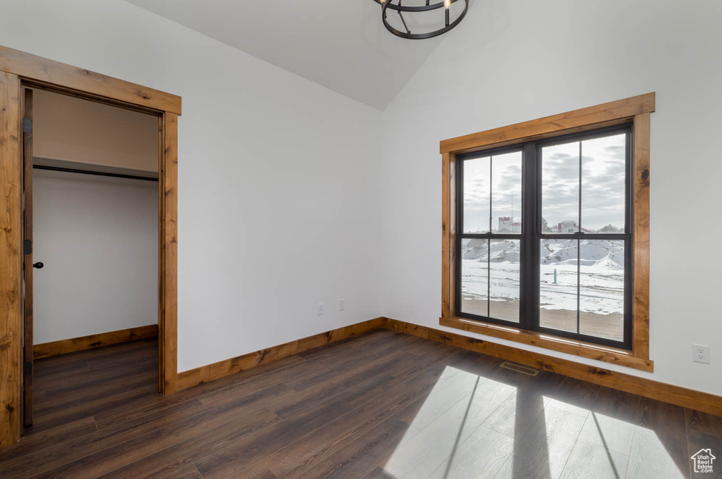 Unfurnished bedroom with dark hardwood / wood-style flooring, lofted ceiling, and a closet