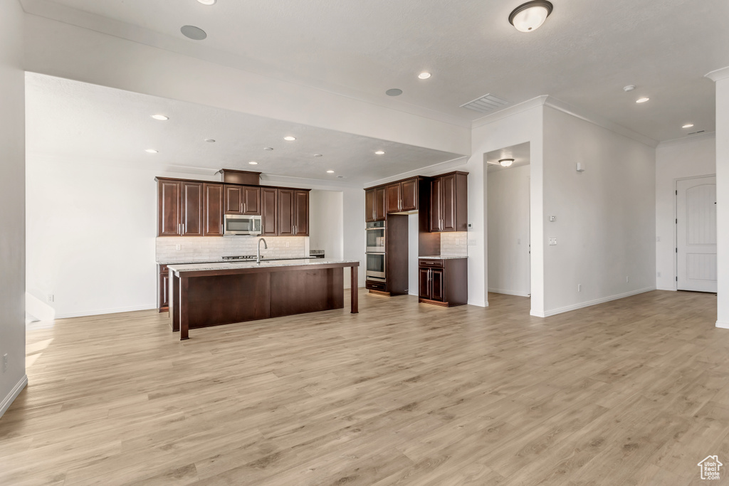 Kitchen featuring tasteful backsplash, sink, appliances with stainless steel finishes, light hardwood / wood-style floors, and dark brown cabinetry