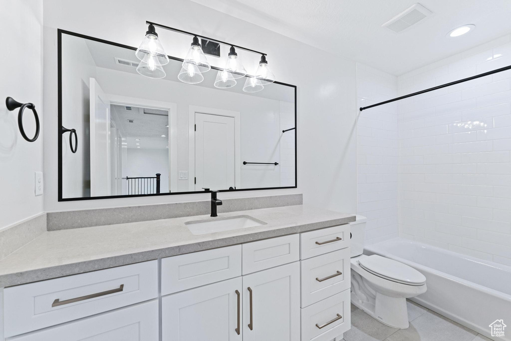 Full bathroom with tile floors, tiled shower / bath, vanity, and toilet