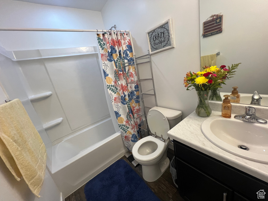 Full bathroom featuring shower / bath combo, hardwood / wood-style floors, large vanity, and toilet