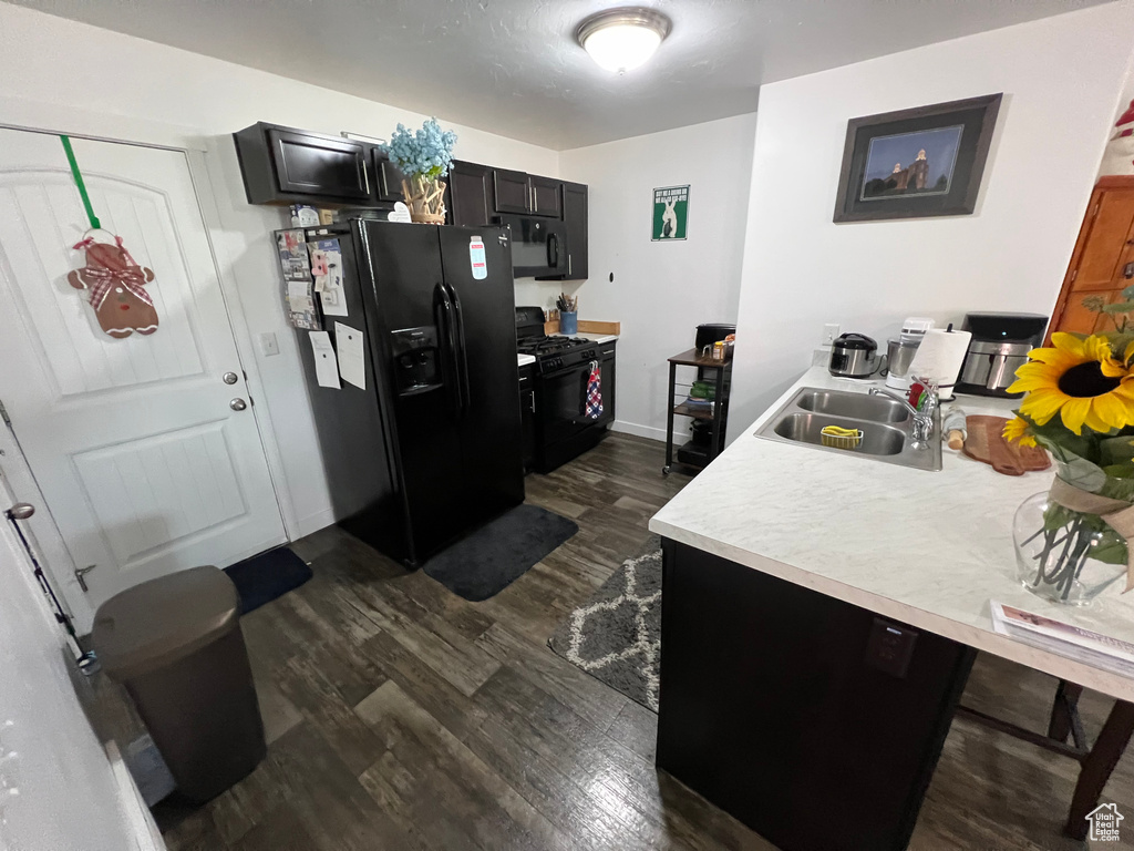 Kitchen with black appliances, dark hardwood / wood-style flooring, and sink