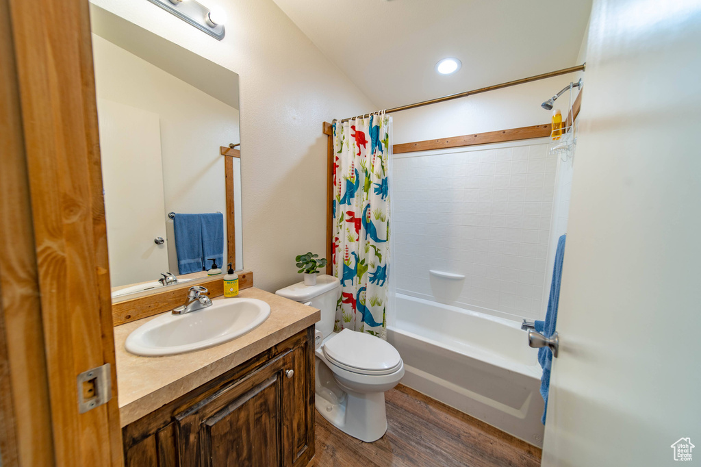 Full bathroom featuring toilet, hardwood / wood-style floors, large vanity, and shower / tub combo with curtain