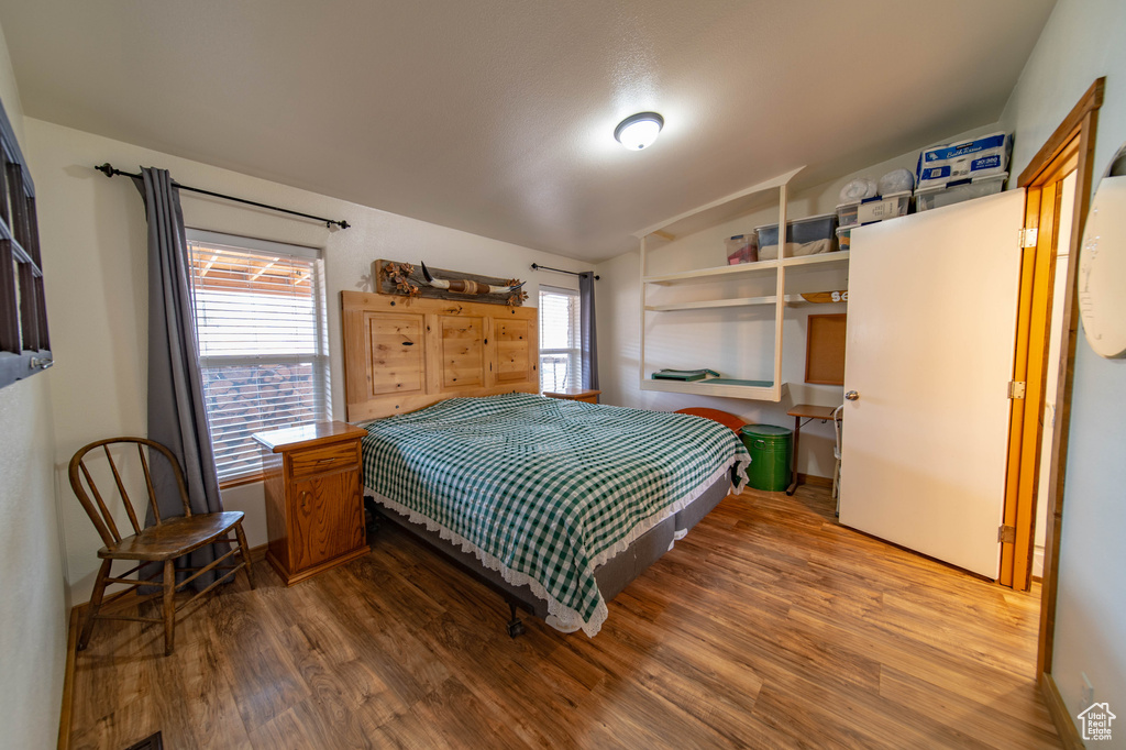 Bedroom featuring multiple windows, vaulted ceiling, and hardwood / wood-style flooring