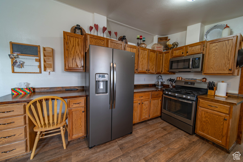 Kitchen with dark hardwood / wood-style floors and appliances with stainless steel finishes