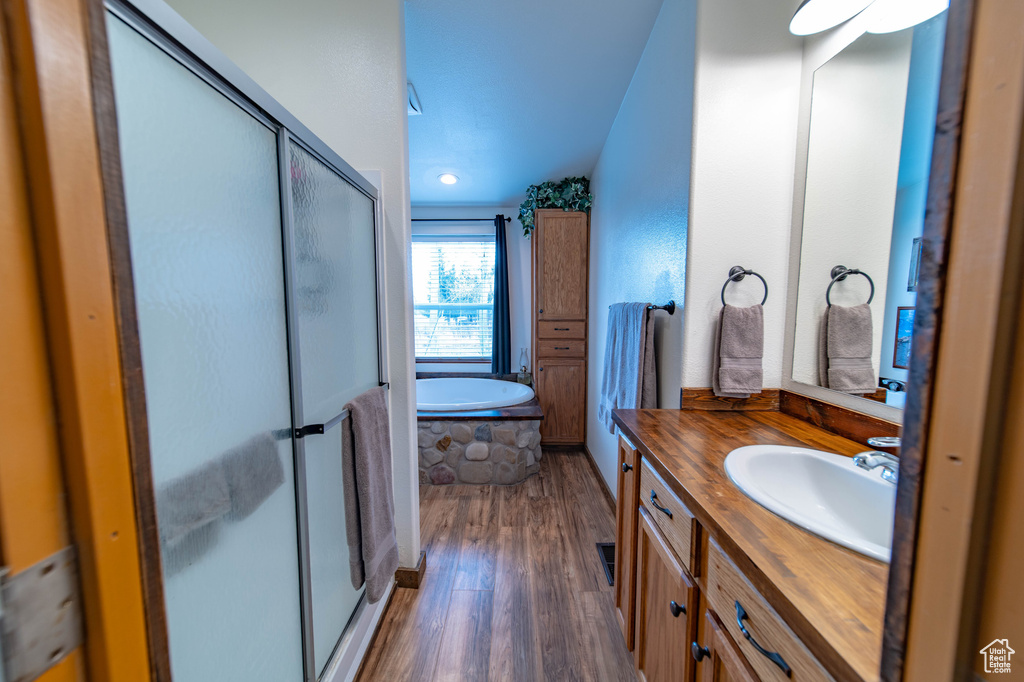Bathroom featuring vanity, separate shower and tub, hardwood / wood-style floors, and lofted ceiling
