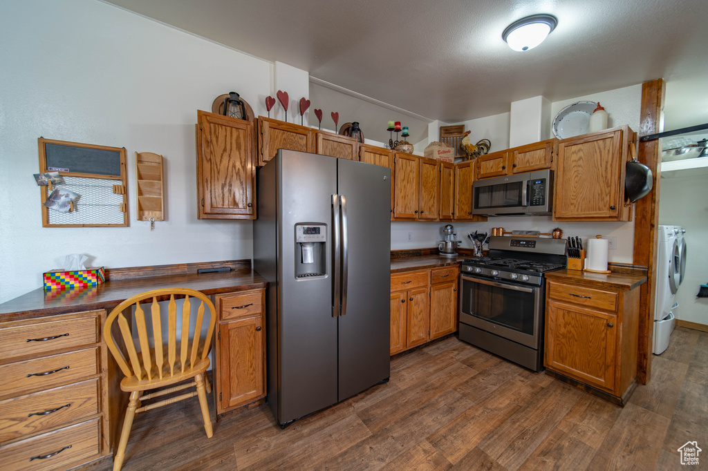 Kitchen with dark hardwood / wood-style flooring, stainless steel appliances, and washer and dryer