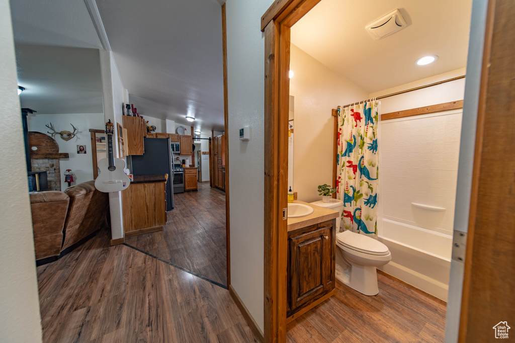 Full bathroom with a fireplace, vanity, toilet, wood-type flooring, and shower / bath combination with curtain