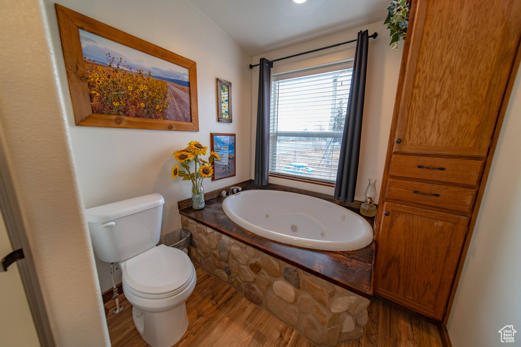 Bathroom featuring hardwood / wood-style flooring, a washtub, and toilet