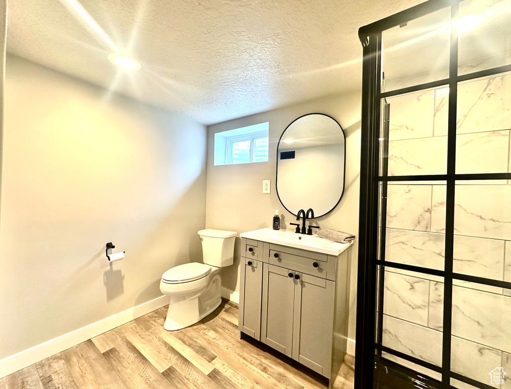 Bathroom with wood-type flooring, vanity, a textured ceiling, and toilet