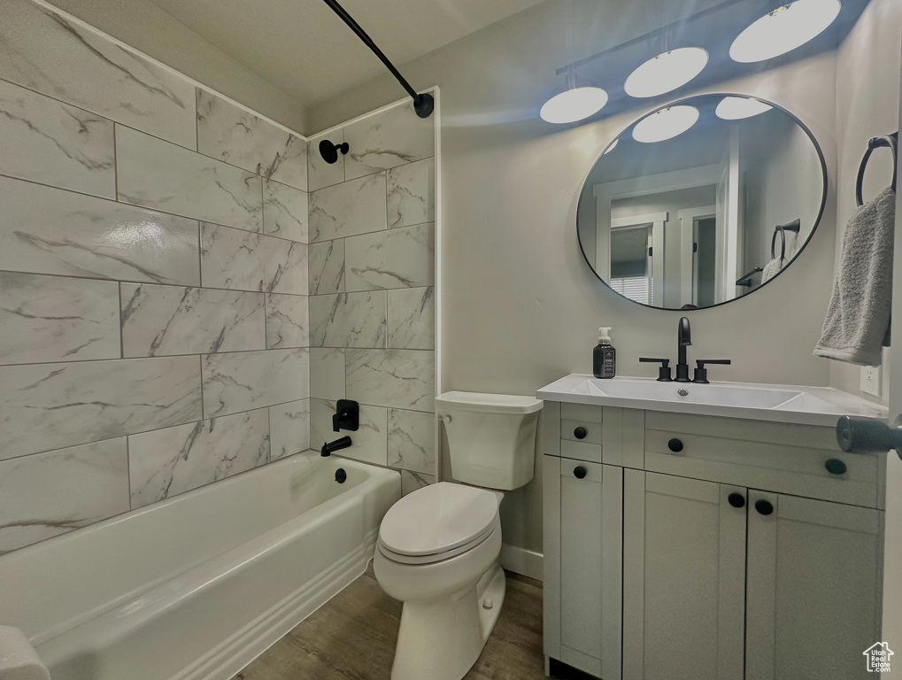 Full bathroom featuring vanity, toilet, hardwood / wood-style floors, and tiled shower / bath combo