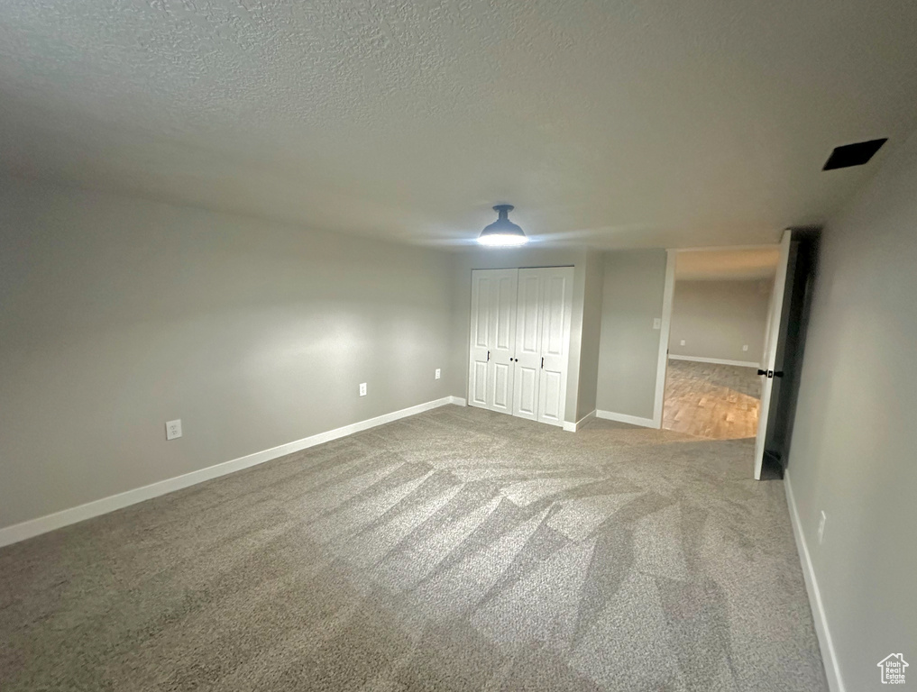 Unfurnished bedroom with a textured ceiling, light colored carpet, and a closet
