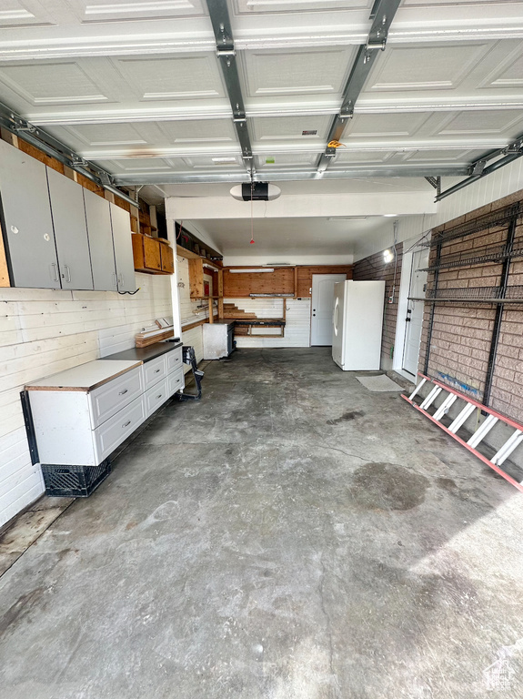 Garage featuring white fridge and a garage door opener