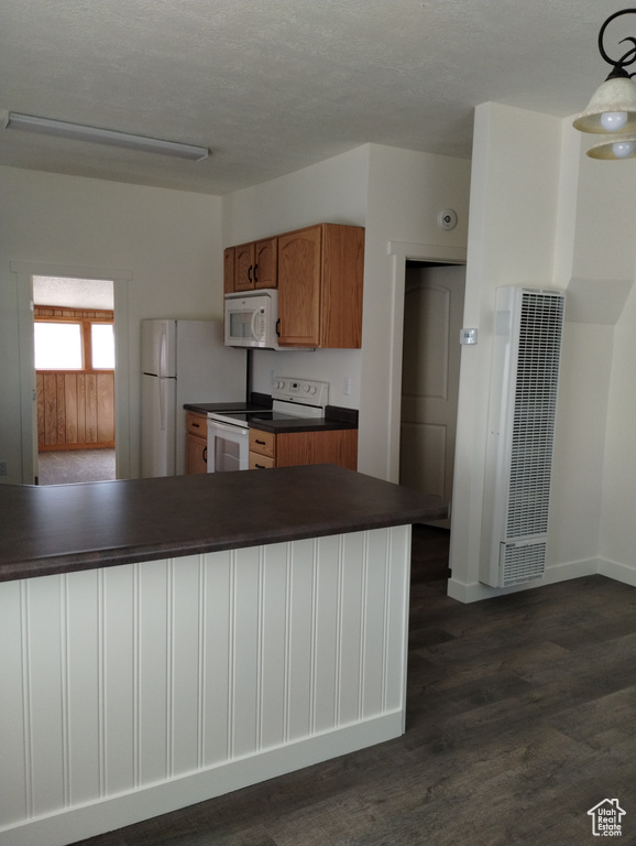 Kitchen featuring white appliances, dark hardwood / wood-style flooring, and pendant lighting