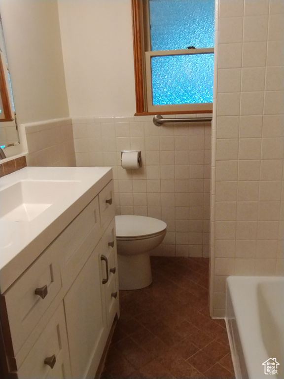 Bathroom with vanity, tasteful backsplash, toilet, tile floors, and tile walls
