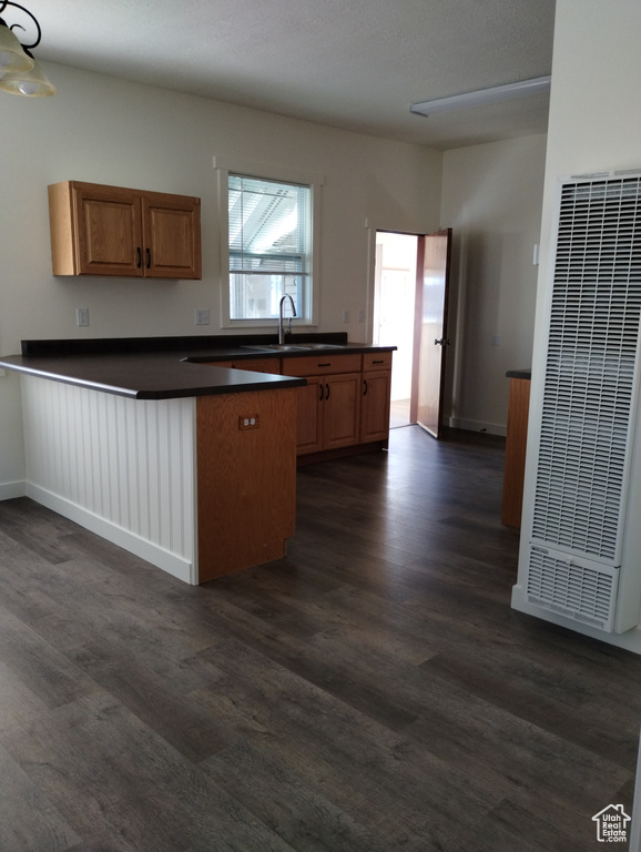 Kitchen featuring dark hardwood / wood-style flooring, kitchen peninsula, and sink