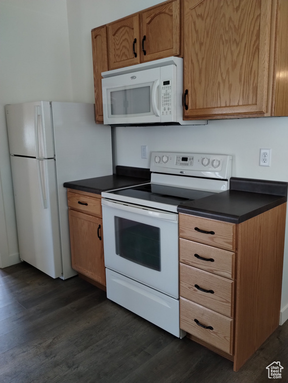 Kitchen with white appliances and dark wood-type flooring
