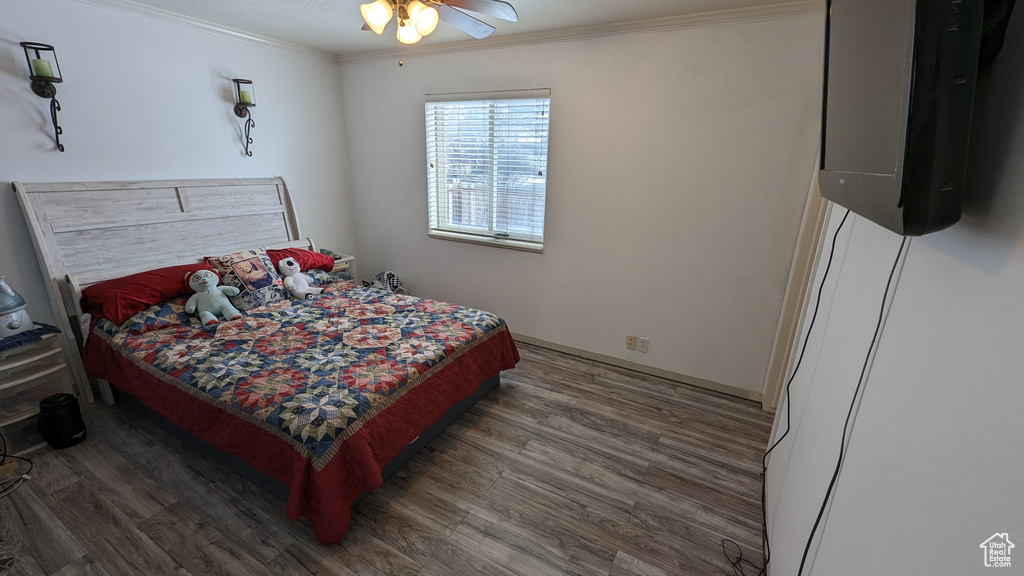 Bedroom featuring dark wood-type flooring, ceiling fan, and ornamental molding