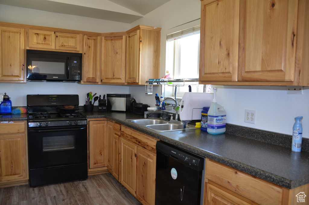 Kitchen featuring black appliances, dark wood-type flooring, and sink
