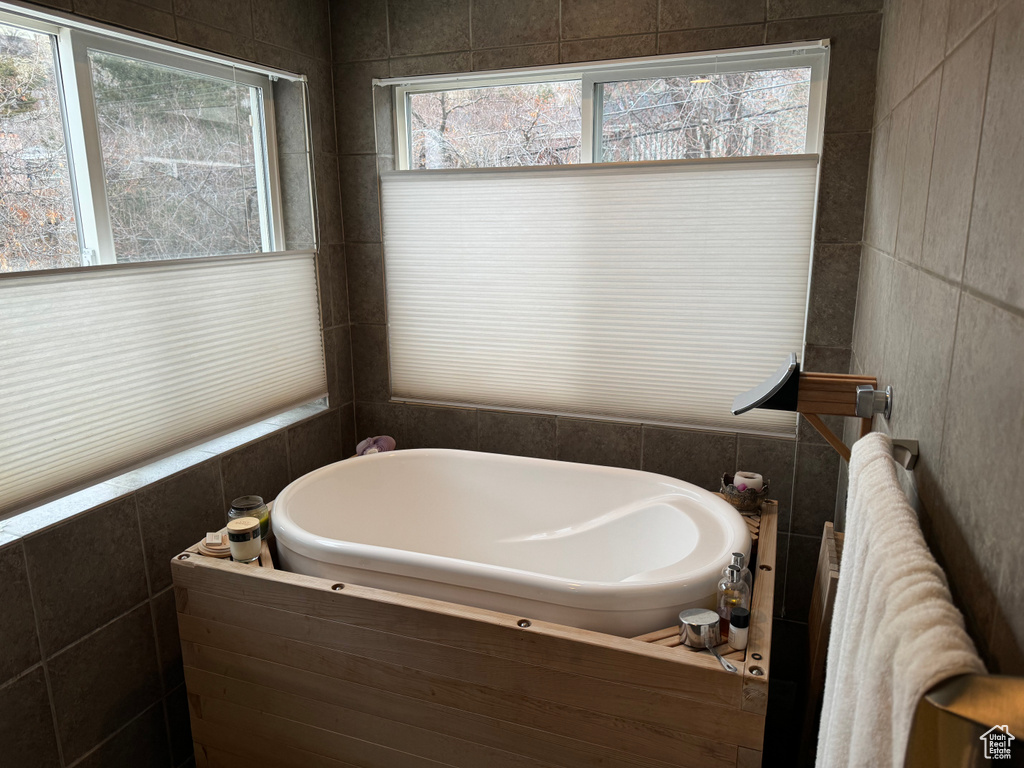 Bathroom with a bathing tub, tile walls, and radiator heating unit