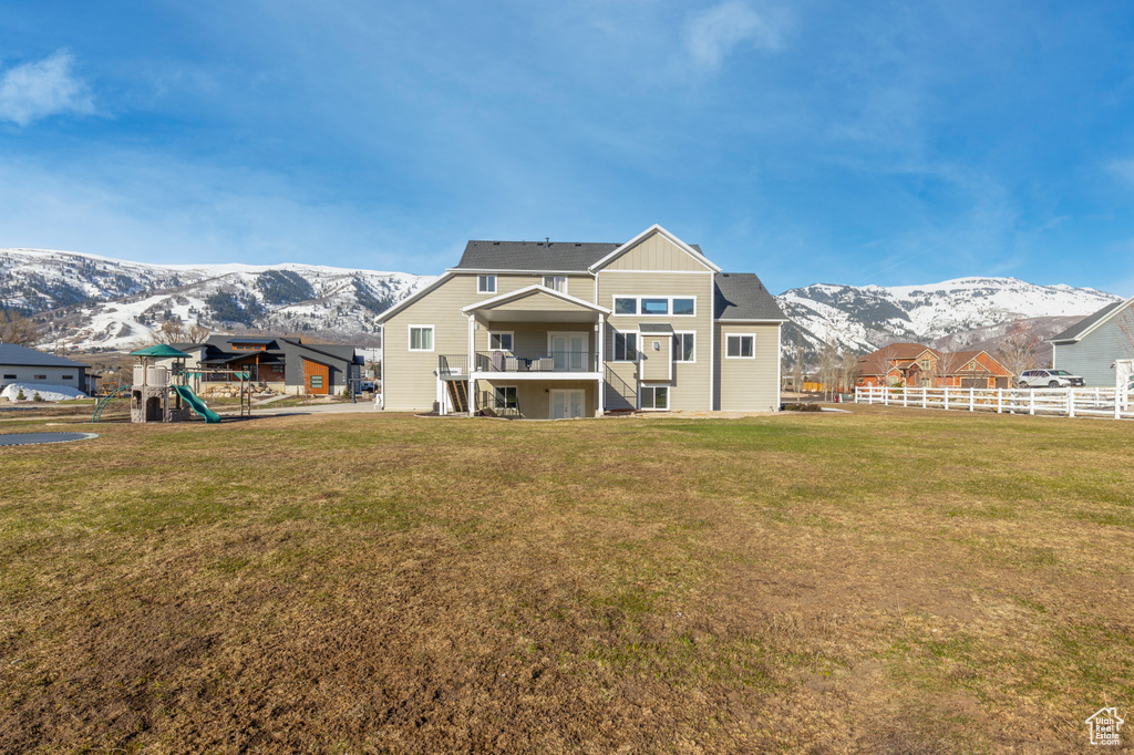 Rear view of property with a mountain view, a lawn, and a playground