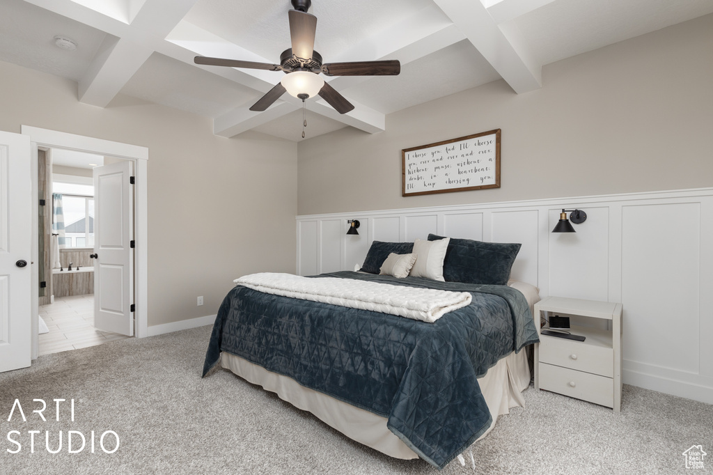 Bedroom featuring ceiling fan, light colored carpet, ensuite bathroom, coffered ceiling, and beam ceiling